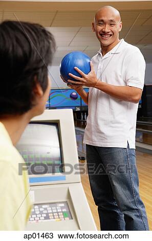 Man standing in bowling ally, holding bowling ball View Large Photo Image Stock Image - Man standing in bowling ally, holding bowling ball. Fotosearch