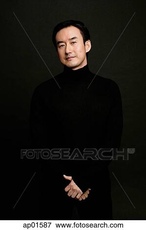 Man standing, looking at camera, black background View Large Photo Image Stock Photo - Man standing, looking at camera, black background. Fotosearch