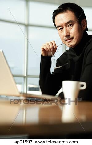 Man using laptop, looking at camera View Large Photo Image Stock Photo - Man using laptop, looking at camera. Fotosearch