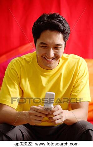 Stock Image - Man using mobile phone, smiling. Fotosearch