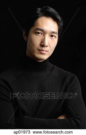 Stock Image - Man wearing black turtleneck against black background. Fotosearch