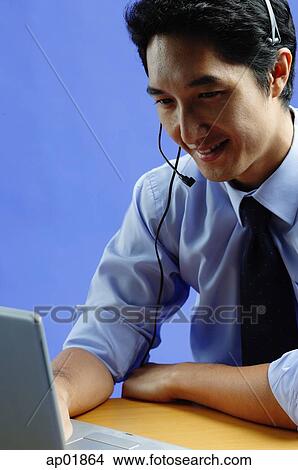 Man wearing headset, using laptop View Large Photo Image Picture - Man wearing headset, using laptop. Fotosearch