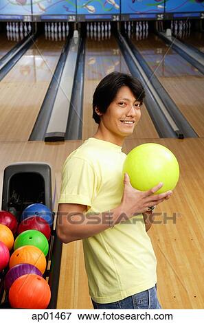 Stock Photo - Man with bowling ball, looking at camera. Fotosearch