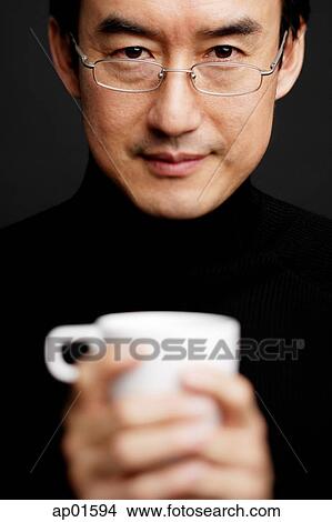 Man with glasses, holding mug, black background View Large Photo Image Picture - Man with glasses, holding mug, black background. Fotosearch
