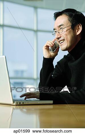 Stock Photo - Man with laptop, on the phone. Fotosearch