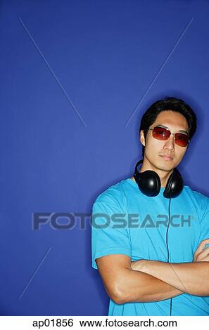 Man with sunglasses, headphones around his neck, arms crossed View Large Photo Image Stock Photograph - Man with sunglasses, headphones around his neck, arms crossed. Fotosearch