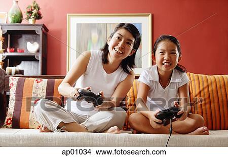 Picture - Mother and daughter in living room, playing video game. Fotosearch