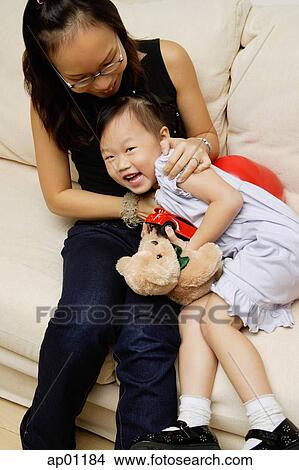 Mother and daughter on sofa, daughter smiling at camera View Large Photo Image Picture - Mother and daughter on sofa, daughter smiling at camera. Fotosearch