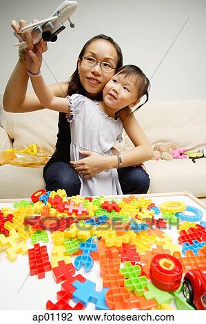 Stock Image - Mother and daughter playing toy airplane. Fotosearch