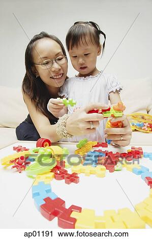 Stock Image - Mother and daughter playing with puzzle pieces. Fotosearch