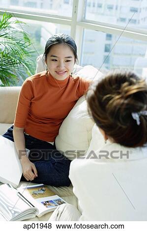Mother and daughter sitting on sofa View Large Photo Image Stock Photo - Mother and daughter sitting on sofa. Fotosearch