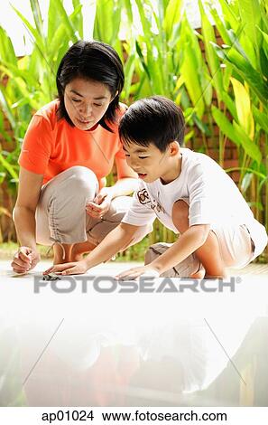 Mother and son crouching, looking at terrapin on floor View Large Photo Image Picture - Mother and son crouching, looking at terrapin on floor. Fotosearch