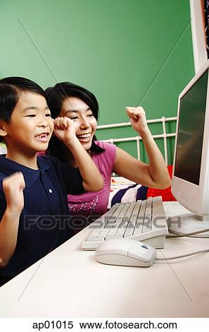 Mother and son looking at computer, smiling, making fists View Large Photo Image Stock Photography - Mother and son looking at computer, smiling, making fists. Fotosearch