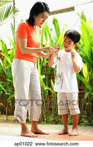 Stock Image - Mother and son standing, looking at terrapin. Fotosearch
