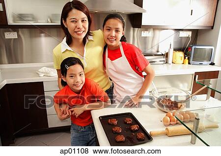 Mother and two daughters in kitchen, looking at camera View Large Photo Image Stock Photo - Mother and two daughters in kitchen, looking at camera. Fotosearch