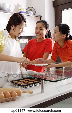 Mother and two daughters in kitchen, with tray of cookies View Large Photo Image Stock Photo - Mother and two daughters in kitchen, with tray of cookies. Fotosearch
