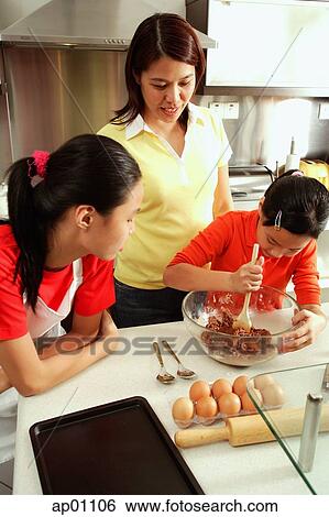 Mother and two daughters in kitchen, one daughter holding spoon and bowl View Large Photo Image Stock Photograph - Mother and two daughters in kitchen, one daughter holding spoon and bowl. Fotosearch