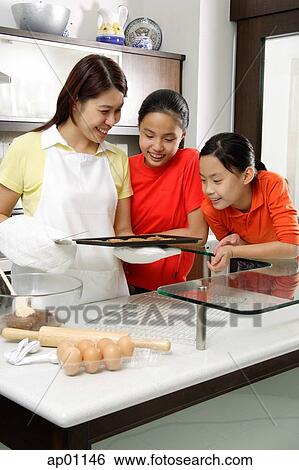 Mother and two daughters in kitchen, looking at tray of cookies View Large Photo Image Stock Photograph - Mother and two daughters in kitchen, looking at tray of cookies. Fotosearch