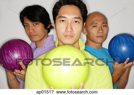 Stock Photo - Three men holding bowling balls, looking at camera. Fotosearch