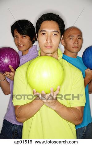 Stock Photograph - Three men standing carrying bowling balls, looking at camera. Fotosearch