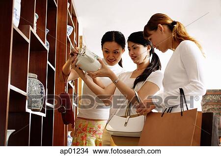 Three women studying teapot in antique shop View Large Photo Image Picture - Three women studying teapot in antique shop. Fotosearch