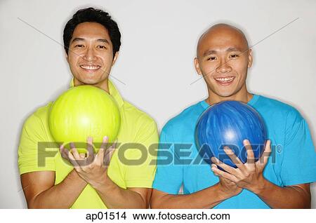 Two men standing side by side, carrying bowling balls, smiling at camera View Large Photo Image Picture - Two men standing side by side, carrying bowling balls, smiling at camera. Fotosearch