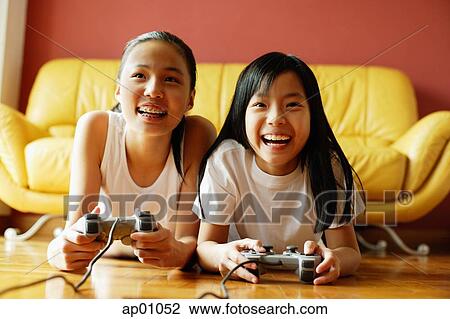 Two sisters in living room, lying on floor playing video games View Large Photo Image Stock Image - Two sisters in living room, lying on floor playing video games. Fotosearch