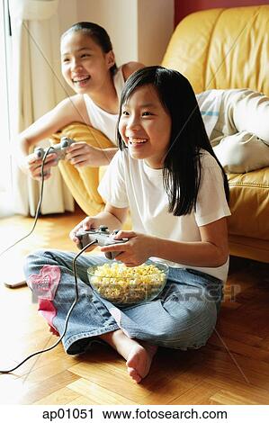 Two sisters in living room, playing video games View Large Photo Image Stock Image - Two sisters in living room, playing video games. Fotosearch