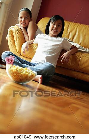 Two sisters sitting in living room, looking at camera View Large Photo Image Stock Photo - Two sisters sitting in living room, looking at camera. Fotosearch