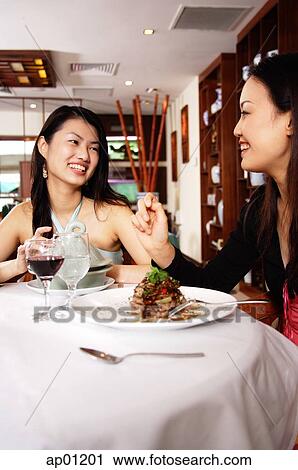 Stock Image - Two women eating in restaurant. Fotosearch