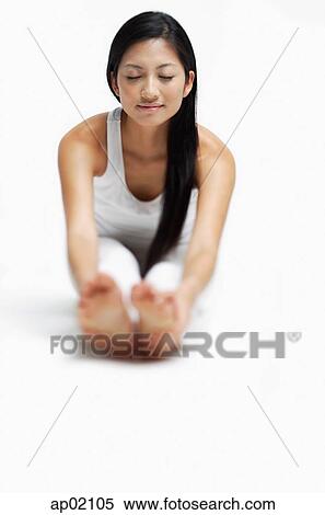 Woman doing yoga, sitting on floor, stretching, holding feet, eyes closed View Large Photo Image Stock Photography - Woman doing yoga, sitting on floor, stretching, holding feet, eyes closed. Fotosearch