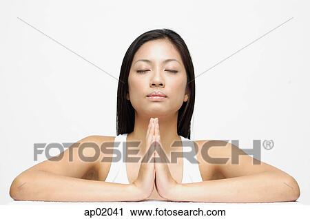 Stock Image - Woman eyes closed, hands together. Fotosearch