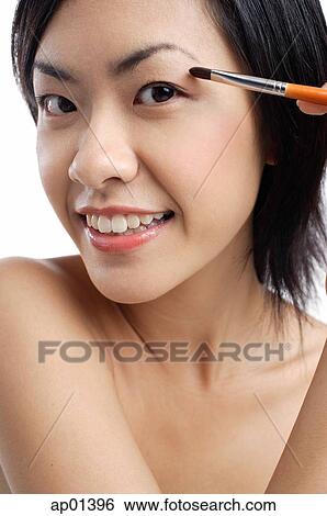 Woman holding brush, applying eyeshadow View Large Photo Image Stock Photograph - Woman holding brush, applying eyeshadow. Fotosearch