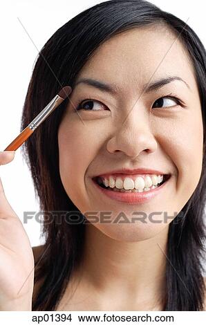 Woman holding eyeshadow brush, looking away View Large Photo Image Picture - Woman holding eyeshadow brush, looking away. Fotosearch