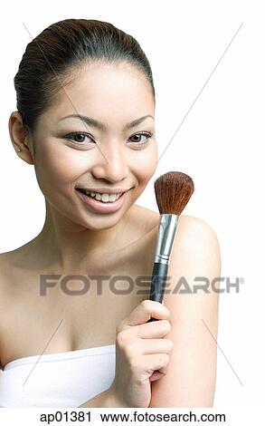 Woman holding make-up brush, smiling at camera View Large Photo Image Stock Image - Woman holding make-up brush, smiling at camera. Fotosearch