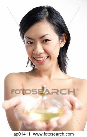 Woman holding perfume bottle, focus on the background View Large Photo Image Stock Image - Woman holding perfume bottle, focus on the background. Fotosearch