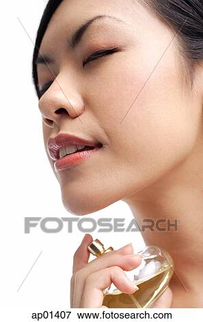 Woman holding perfume bottle, spraying on neck, eyes closed View Large Photo Image Stock Photo - Woman holding perfume bottle, spraying on neck, eyes closed. Fotosearch