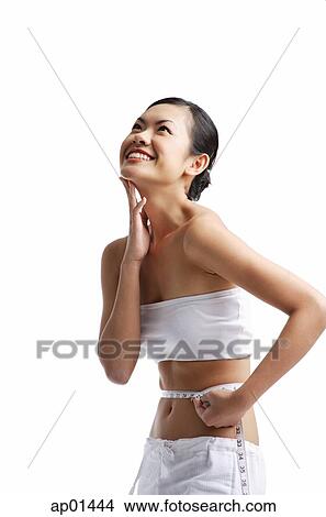 Woman holding tape measure around waist, hand on chin, smiling View Large Photo Image Picture - Woman holding tape measure around waist, hand on chin, smiling. Fotosearch