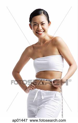 Woman holding tape measure around waist, looking at camera, portrait View Large Photo Image Stock Photo - Woman holding tape measure around waist, looking at camera, portrait. Fotosearch