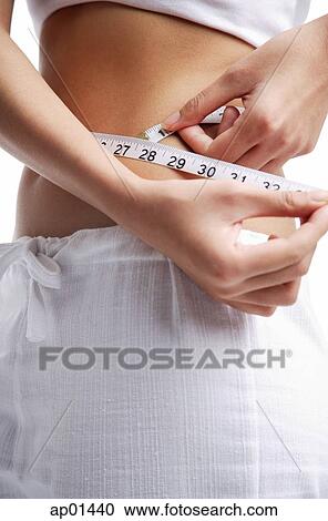 Woman holding tape measure around waist View Large Photo Image Stock Image - Woman holding tape measure around waist. Fotosearch
