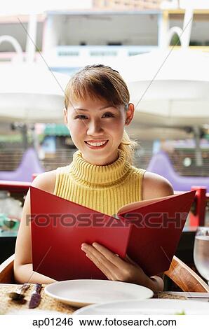 Woman in cafe, holding menu, looking at camera View Large Photo Image Stock Photograph - Woman in cafe, holding menu, looking at camera. Fotosearch