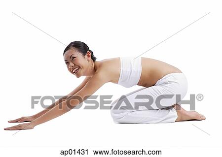 Stock Image - Woman kneeling on floor stretching. Fotosearch