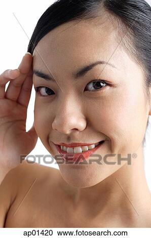 Stock Image - Woman looking at camera, hand on head. Fotosearch