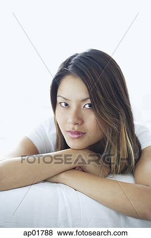 Stock Photo - Woman looking at camera, lying on front, arms crossed. Fotosearch
