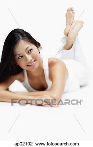 Woman lying on front, legs crossed at the ankle, smiling, looking away View Large Photo Image Stock Image - Woman lying on front, legs crossed at the ankle, smiling, looking away. Fotosearch