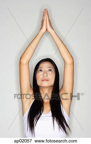 Stock Photo - Woman practicing yoga, arms outstretched, hands together. Fotosearch