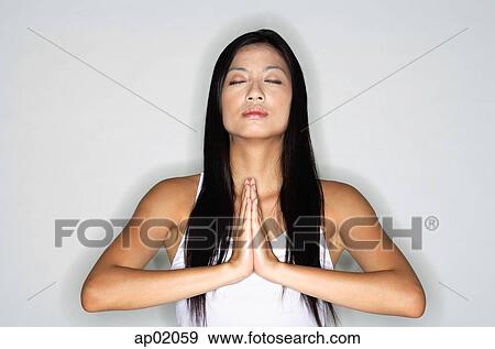 Stock Photo - Woman practicing yoga, hands together, eyes closed. Fotosearch