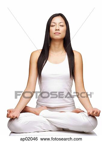 Stock Photograph - Woman practicing yoga, sitting in lotus position, eyes closed. Fotosearch