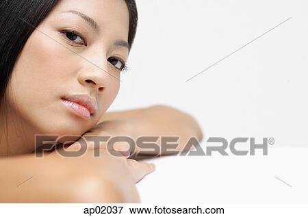 Stock Photo - Woman resting head on arms, looking at camera, side view. Fotosearch
