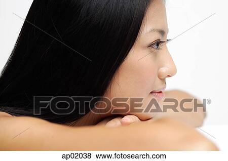 Stock Photo - Woman resting head on arms, looking away, side view. Fotosearch